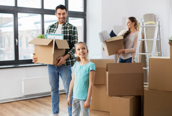 mortgage, family and real estate concept - happy mother, father and little daughter with stuff in boxes moving to new home